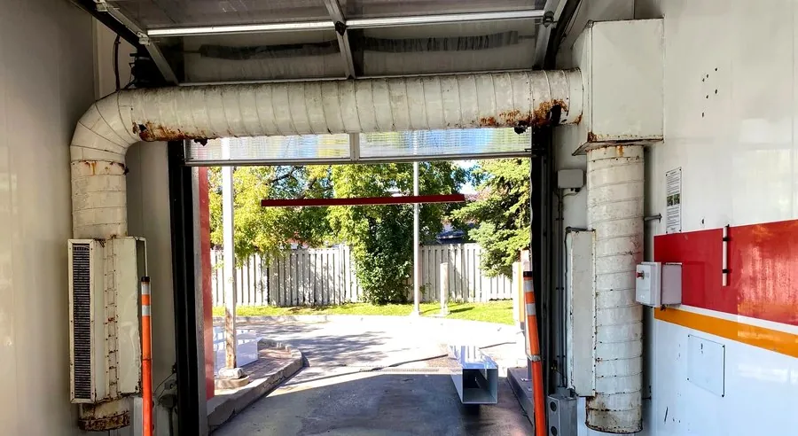 Old, corroded HVAC ductwork and dryer blower unit at a Hamilton commercial car wash before replacement
