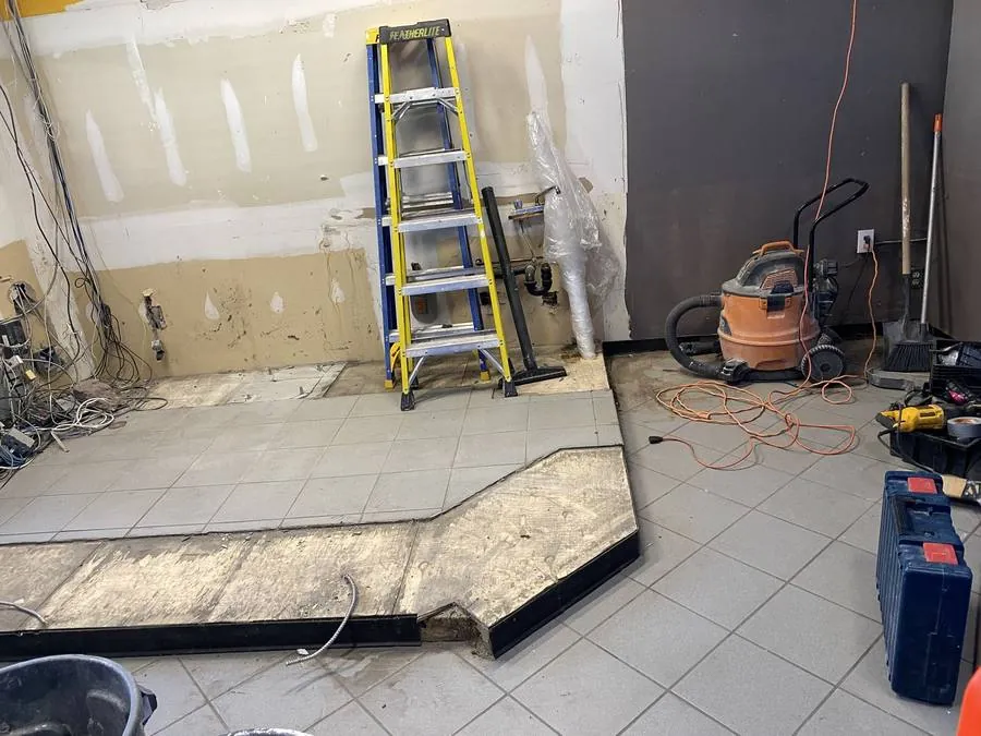 Commercial space in Hamilton before tile demolition, showing existing flooring and exposed wiring during a strip-out