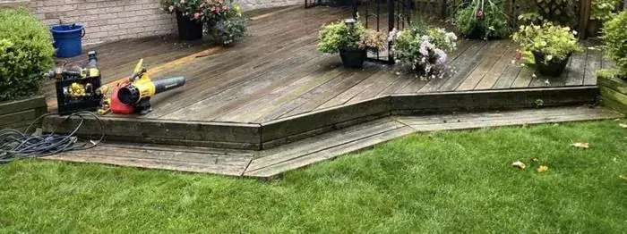 Wood deck in a Hamilton backyard before demolition, with planters and tools staged for the job