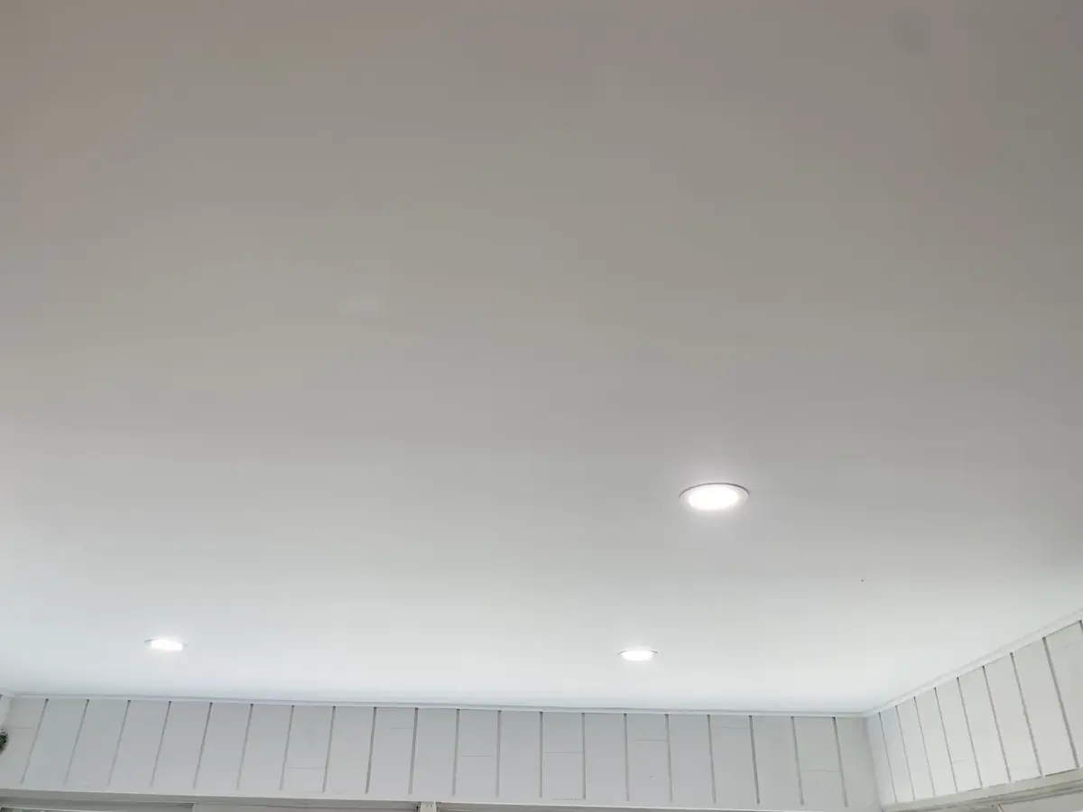 Smooth painted ceiling with recessed lights above white wall panelling
