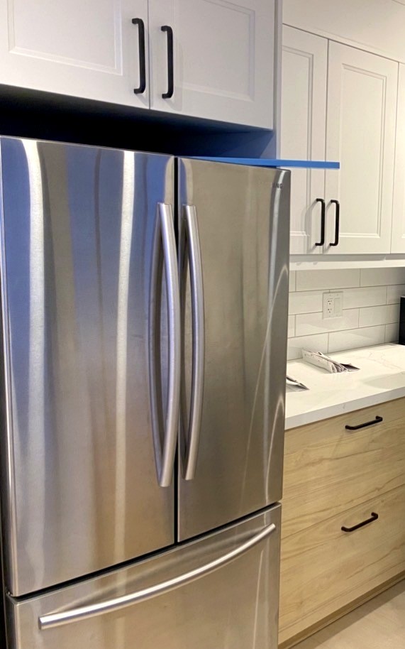 New kitchen cabinetry and stainless steel refrigerator installed during a Hamilton full-home renovation