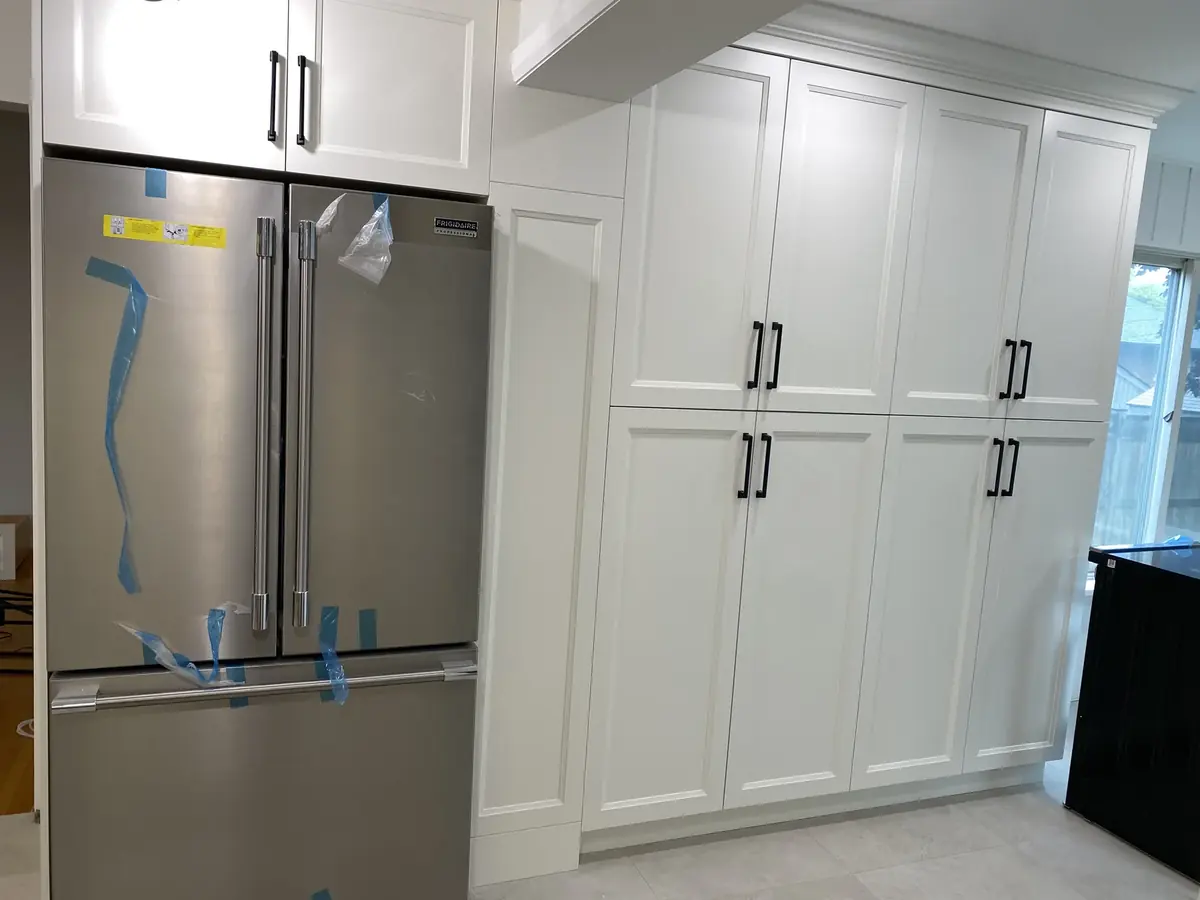 White kitchen cabinetry fitted around a stainless steel refrigerator in Hamilton