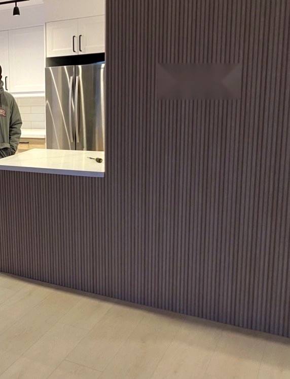 Renovated kitchen in Hamilton with fluted grey island, quartz countertop and stainless steel refrigerator