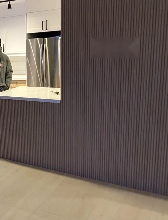 Renovated kitchen in Hamilton with fluted grey island, quartz countertop and stainless steel refrigerator