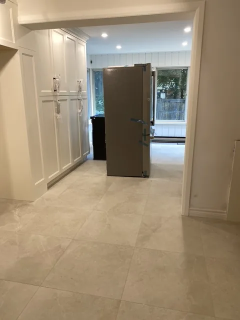 White kitchen cabinetry and large-format floor tile in a completed Hamilton kitchen renovation